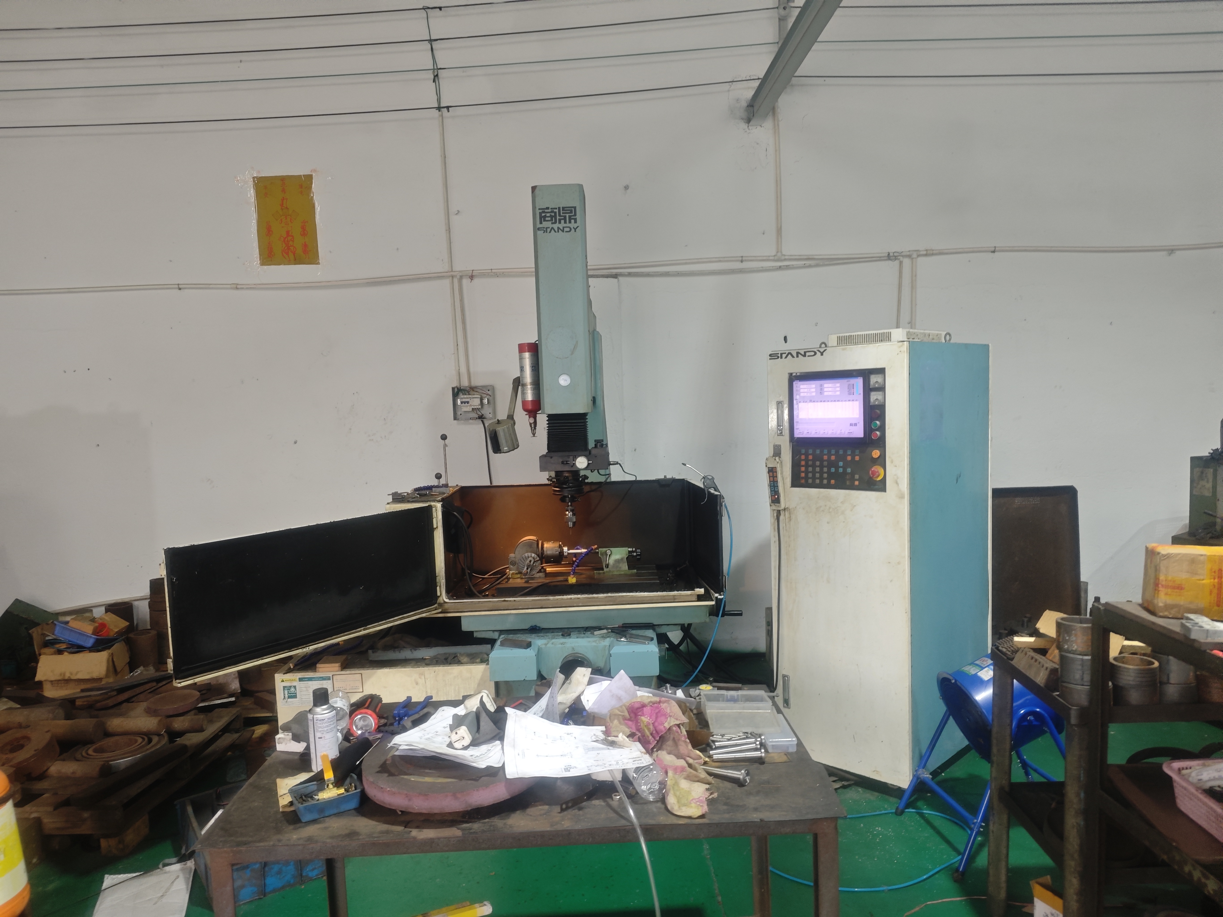 Spark-erosion machine with open work chamber and control cabinet in the workshop
